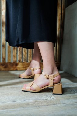 Kadınların ayaklarında bej topuklu sandaletler. Gece elbiseleri için klasik sandaletler.