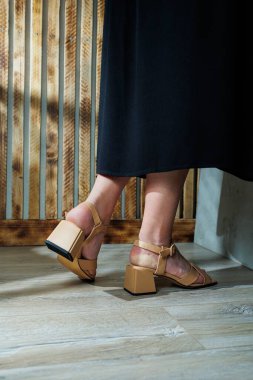 Kadınların ayaklarında bej topuklu sandaletler. Gece elbiseleri için klasik sandaletler.