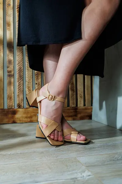 Women\'s beige heeled sandals on women\'s feet. Classic sandals for evening dresses