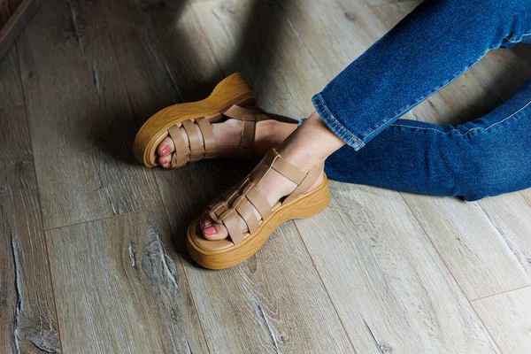 Beige leather sandals on women's feet. Female feet in comfortable casual sandals