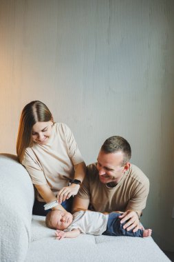 Yeni doğmuş bebekleri olan genç ve mutlu ebeveynler evlerinde kanepede. Beyaz bir arka planda yeni doğmuş bebekleri olan anne ve baba.