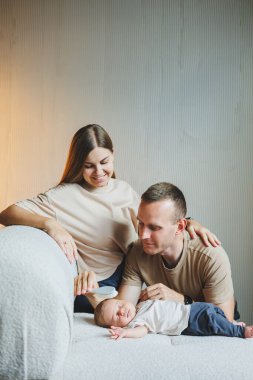 Yeni doğmuş bir bebeği olan genç bir aile. Mutlu anne ve baba çocuklarını öpüyor. Ebeveynler ve kollarında gülümseyen bir çocuk.
