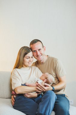 Yeni doğmuş bebeği olan mutlu bir aile. Güzel anne ve baba çocuklarını öpüyor. Anne baba ve gülümseyen çocuk, beyaz arka planda izole edilmiş..