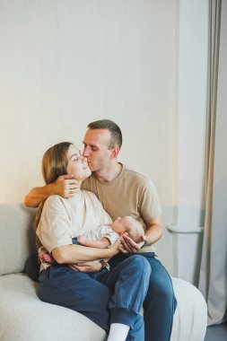 Yeni doğmuş bebeği olan mutlu bir aile. Güzel anne ve baba çocuklarını öpüyor. Anne baba ve gülümseyen çocuk, beyaz arka planda izole edilmiş..