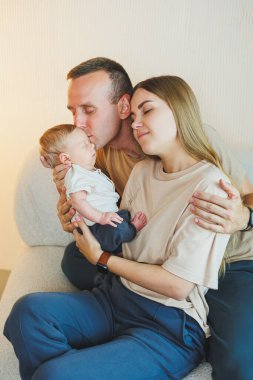 Yeni doğmuş bebeği olan mutlu bir aile. Güzel anne ve baba çocuklarını öpüyor. Anne baba ve gülümseyen çocuk, beyaz arka planda izole edilmiş..