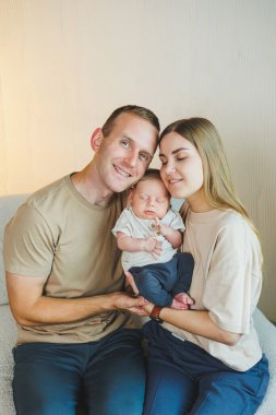 Yeni doğmuş bebeği olan mutlu bir aile. Güzel anne ve baba çocuklarını öpüyor. Anne baba ve gülümseyen çocuk, beyaz arka planda izole edilmiş..