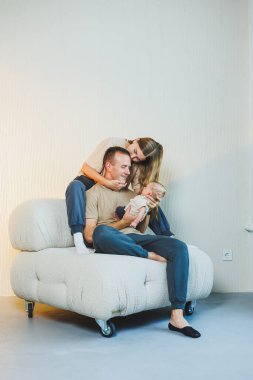 Yeni doğmuş bebeği olan mutlu bir aile. Güzel anne ve baba çocuklarını öpüyor. Anne baba ve gülümseyen çocuk, beyaz arka planda izole edilmiş..