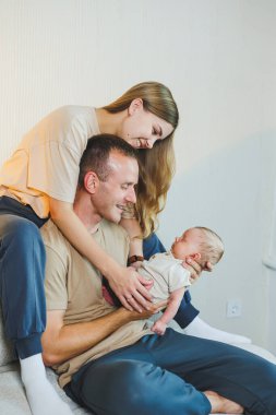 Yeni doğmuş bebeği olan mutlu bir aile. Güzel anne ve baba çocuklarını öpüyor. Anne baba ve gülümseyen çocuk, beyaz arka planda izole edilmiş..