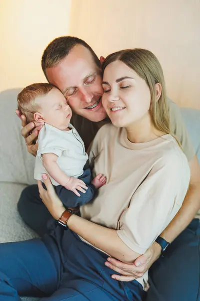 Happy mother and father hugging their newborn baby. Parents and a smiling child in their arms. A young family with a newborn baby.
