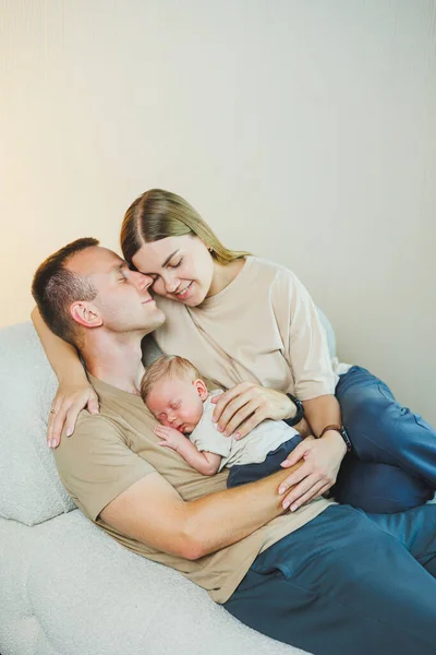 Happy mother and father hugging their newborn baby. Parents and a smiling child in their arms. A young family with a newborn baby.