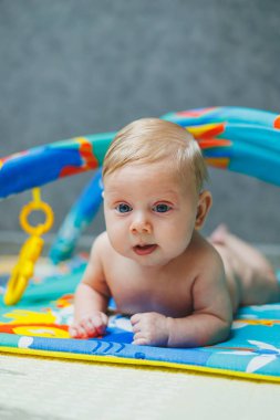 2 aylık bir bebek gelişim paspasına uzanıp oyuncaklarla oynuyor. Oynarken, çocuk dünyayı tanımaya başlar ve şekilleri ve renkleri öğrenir. Çocuk gelişimi