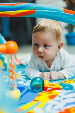 Bir bebek iki ay boyunca gelişim minderinde oynar. Küçük çocuklar için oyuncak halı..