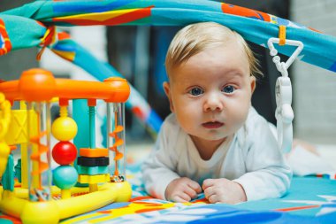 Bir bebek iki ay boyunca gelişim minderinde oynar. Küçük çocuklar için oyuncak halı..