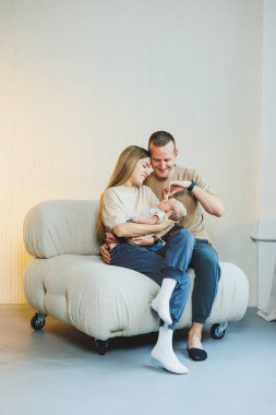 Yeni doğmuş bebeği olan mutlu bir aile. Güzel anne ve baba çocuklarını öpüyor. Anne baba ve gülümseyen çocuk, beyaz arka planda izole edilmiş..