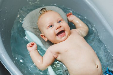 Yeni doğmuş bir bebek banyo yapar. Ebeveynler çocuğu yıkıyor. Yeni doğan banyo yapar. Yeni doğan gülümsüyor. Bebek bakımı