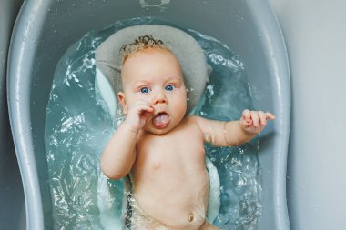 Bebeğin ilk banyosu. Yeni doğmuş bir bebeğe bakmak. Bir bebeği küvette yıkamak. Yeni doğmuş bir bebek suda banyo yapıyor..