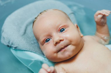 Bebeğin ilk banyosu. Yeni doğmuş bir bebeğe bakmak. Bir bebeği küvette yıkamak. Yeni doğmuş bir bebek suda banyo yapıyor..