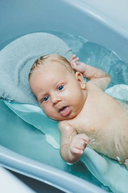 Bebeğin ilk banyosu. Yeni doğmuş bir bebeğe bakmak. Bir bebeği küvette yıkamak.