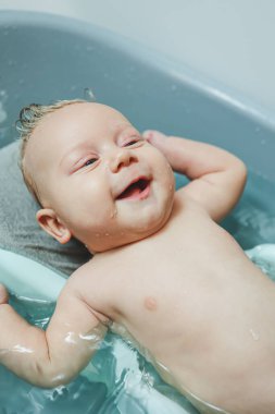 Bebeğin ilk banyosu. Yeni doğmuş bir bebeğe bakmak. Bir bebeği küvette yıkamak. Yeni doğmuş bir bebek suda banyo yapıyor..