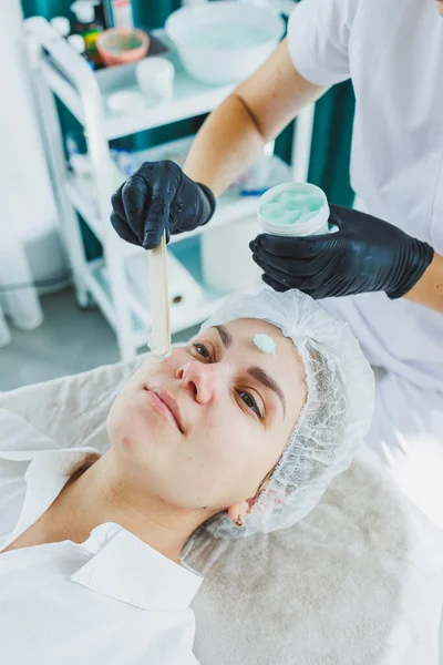 The office of a beautician applying a mask to a woman\'s face in a spa salon, view above. Aesthetic procedure. Care mask for facial skin.