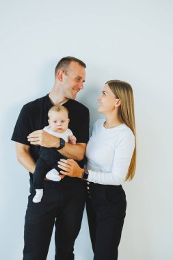 Genç bir anne ve baba, 4 aylık oğullarını kucağında tutuyor. Küçük çocuklu şık bir aile.