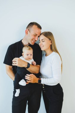 Genç bir anne ve baba, 4 aylık oğullarını kucağında tutuyor. Küçük çocuklu şık bir aile.