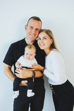 Genç bir anne ve baba, 4 aylık oğullarını kucağında tutuyor. Küçük çocuklu şık bir aile.