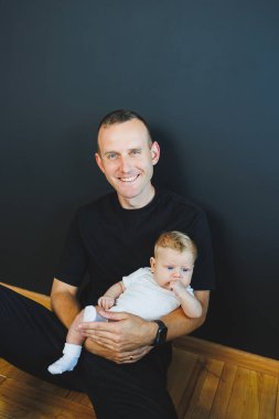 Gülümseyen genç baba yeni doğmuş oğlunu kollarına aldı. Mutlu baba. Oğlu ve babası