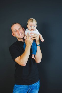 Gülümseyen genç baba yeni doğmuş oğlunu kollarına aldı. Mutlu baba. Oğlu ve babası