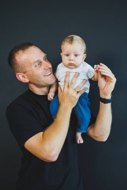 Gülümseyen genç baba yeni doğmuş oğlunu kollarına aldı. Mutlu baba. Oğlu ve babası