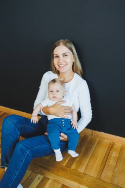 Gülümseyen genç bir anne yeni doğan oğlunu kollarında tutuyor. Mutlu anne. Oğlu ve annesi. Mutlu annelik kavramı