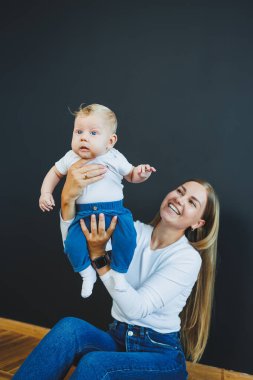 Gülümseyen genç bir anne yeni doğan oğlunu kollarında tutuyor. Mutlu anne. Oğlu ve annesi. Mutlu annelik kavramı