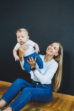 Gülümseyen genç bir anne yeni doğan oğlunu kollarında tutuyor. Mutlu anne. Oğlu ve annesi. Mutlu annelik kavramı
