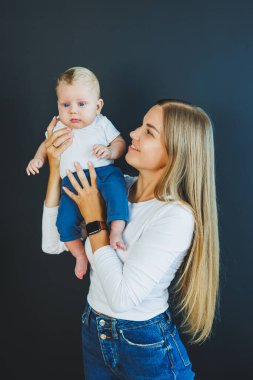 Gülümseyen genç bir anne yeni doğan oğlunu kollarında tutuyor. Mutlu anne. Oğlu ve annesi. Mutlu annelik kavramı