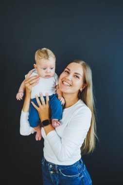 Gülümseyen genç bir anne yeni doğan oğlunu kollarında tutuyor. Mutlu anne. Oğlu ve annesi. Mutlu annelik kavramı