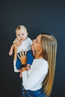 Gülümseyen genç bir anne yeni doğan oğlunu kollarında tutuyor. Mutlu anne. Oğlu ve annesi. Mutlu annelik kavramı