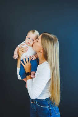 Gülümseyen genç bir anne yeni doğan oğlunu kollarında tutuyor. Mutlu anne. Oğlu ve annesi. Mutlu annelik kavramı
