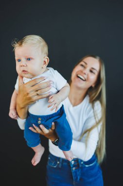 Gülümseyen genç bir anne yeni doğan oğlunu kollarında tutuyor. Mutlu anne. Oğlu ve annesi. Mutlu annelik kavramı