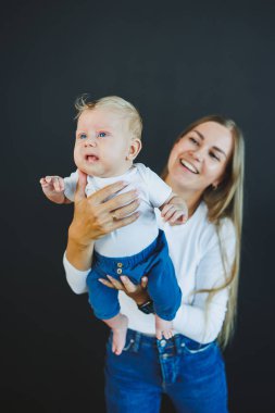 Gülümseyen genç bir anne yeni doğan oğlunu kollarında tutuyor. Mutlu anne. Oğlu ve annesi. Mutlu annelik kavramı