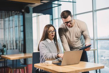 Modern bir ofiste, gündelik giysiler içinde çalışan erkek ve bayan meslektaşlar, modern bir proje için dizüstü bilgisayarla çalışıyorlar..