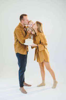 Mutlu genç anne ve baba yeni doğan oğullarını kollarına alıp ona pasta veriyorlar. Ebeveynler doğum günlerini küçük oğullarıyla kutluyorlar. Aile tatili kavramı.