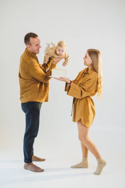 Mutlu genç anne ve baba yeni doğan oğullarını kollarına alıp ona pasta veriyorlar. Ebeveynler doğum günlerini küçük oğullarıyla kutluyorlar. Aile tatili kavramı.