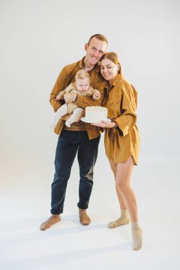 Mutlu genç anne ve baba yeni doğan oğullarını kollarına alıp ona pasta veriyorlar. Ebeveynler doğum günlerini küçük oğullarıyla kutluyorlar. Aile tatili kavramı.