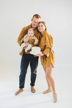 Ebeveynler doğum günlerini küçük oğullarıyla kutluyorlar. Aile tatili kavramı. Genç aileler, oğullarını doğum gününde pastayla kutluyorlar..