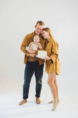 Ebeveynler doğum günlerini küçük oğullarıyla kutluyorlar. Aile tatili kavramı. Genç aileler, oğullarını doğum gününde pastayla kutluyorlar..