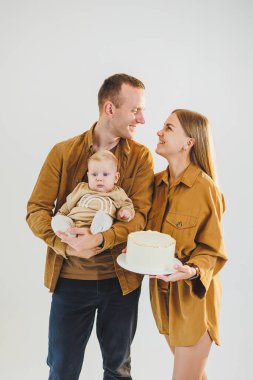 Ebeveynler doğum günlerini küçük oğullarıyla kutluyorlar. Aile tatili kavramı. Genç aileler, oğullarını doğum gününde pastayla kutluyorlar..