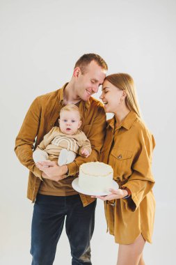 Ebeveynler doğum günlerini küçük oğullarıyla kutluyorlar. Aile tatili kavramı. Genç aileler, oğullarını doğum gününde pastayla kutluyorlar..