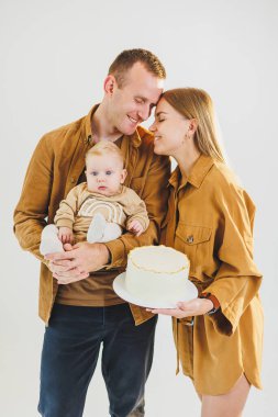 Ebeveynler doğum günlerini küçük oğullarıyla kutluyorlar. Aile tatili kavramı. Genç aileler, oğullarını doğum gününde pastayla kutluyorlar..