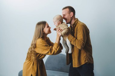 Mutlu bir anne ve baba 4 aylık oğullarını kollarında tutuyor. Mutlu ebeveynlerin yeni doğmuş bir bebekle çekilmiş aile fotoğrafı. Aile kavramı