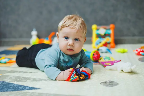 Bebek termal bir mindere uzanıp oynuyor. Yeni doğmuş bir çocuğun öz gelişimi. Çocuk gelişimi için oyuncaklar.